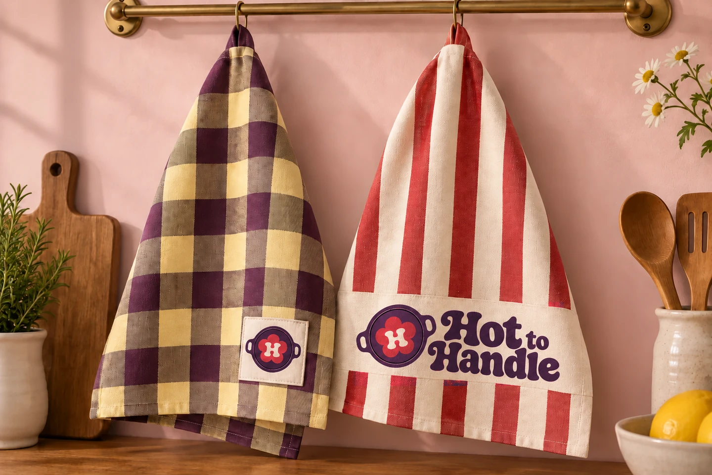 Plum-and-butter checked tea towel beside a cherry-striped towel with Hot to Handle branding